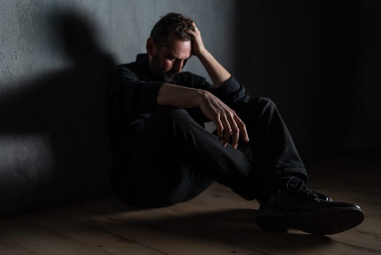 Sad mature man alone in darkness sitting and thinking