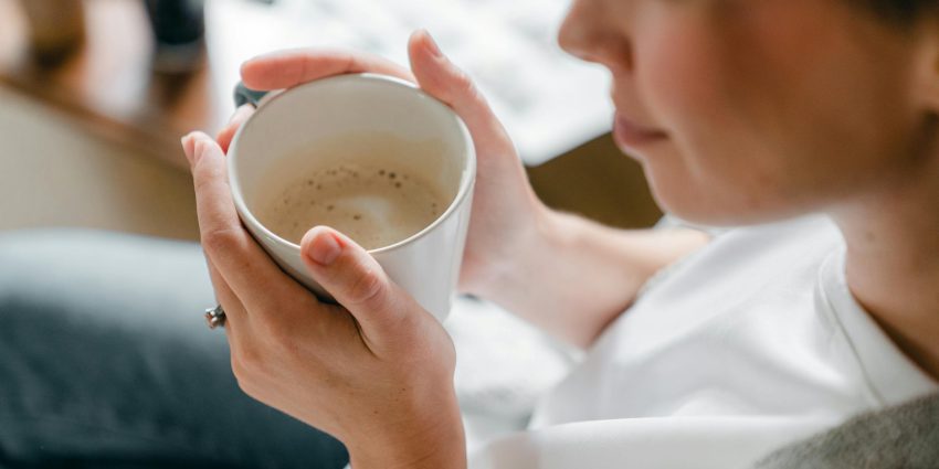 A woman enjoys a warm cup of coffee indoors, capturing a moment of relaxation.